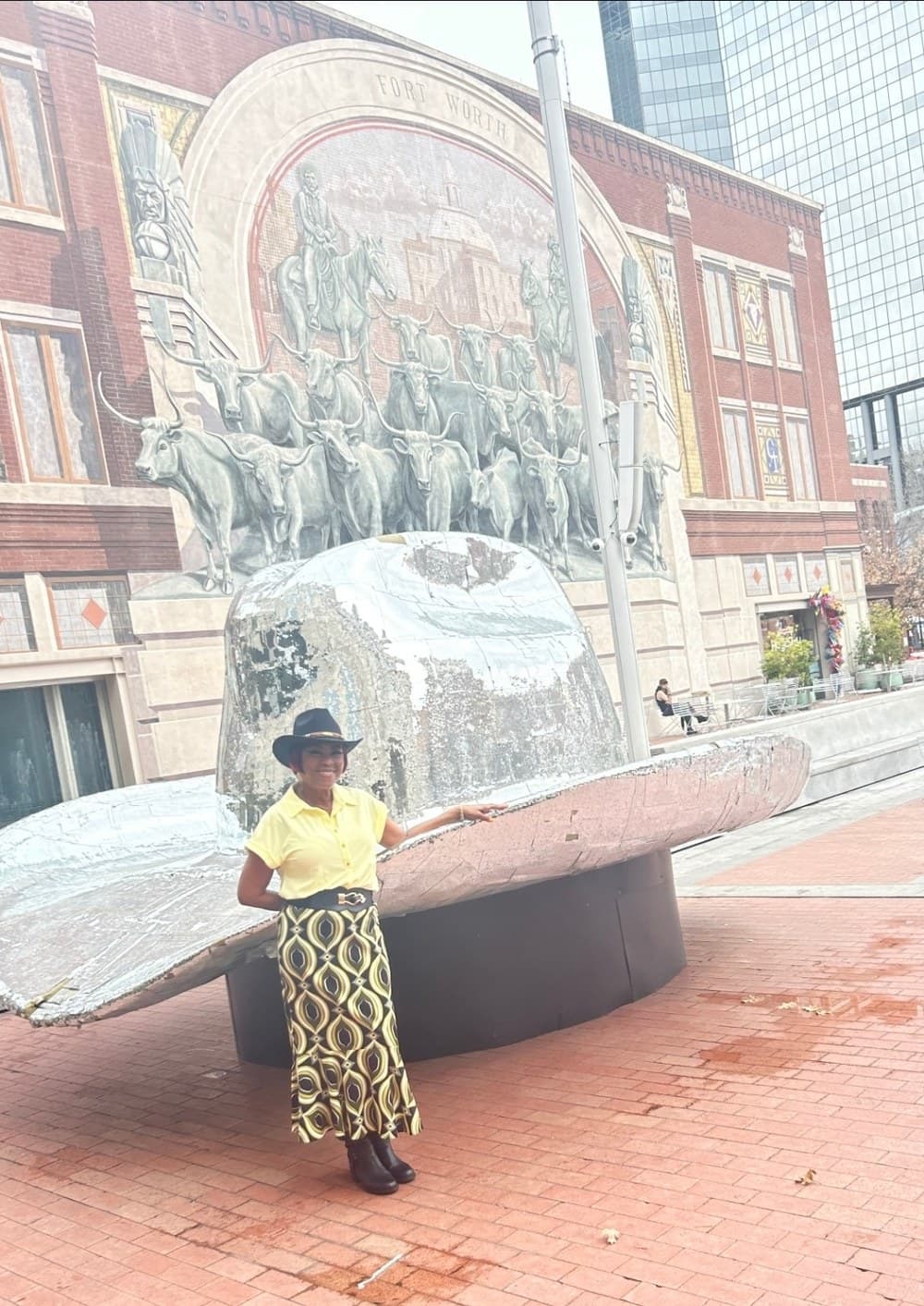 Yvonne standing outdoors in front of the Fort Worth Chisholm Trail mural